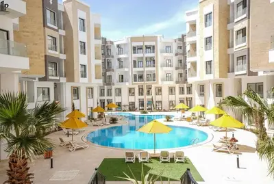 an apartment complex with a swimming pool and yellow umbrellas at Aqua Infinity in Hurghada