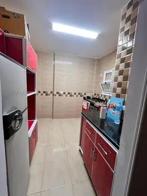 a small kitchen with red cabinets and a refrigerator at Hurghada Promenade Spacious 1-Bedroom Apartment in Makramia Compound in Hurghada