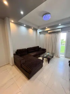 a living room with a brown couch and a table at Hurghada Promenade Spacious 1-Bedroom Apartment in Makramia Compound in Hurghada