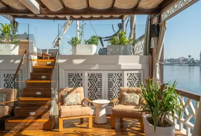 a deck on a boat with two chairs and stairs at HMC Zahra Dahabyia in Luxor