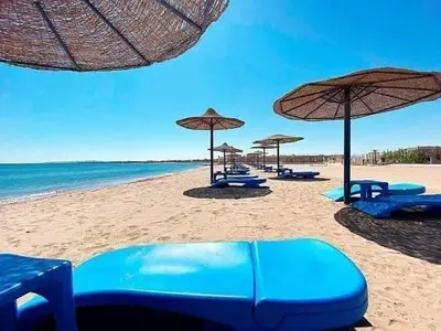 a group of blue chairs and umbrellas on a beach at cecelia resort in Hurghada