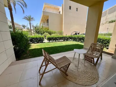 two chairs and a table on a porch with a yard at G-Cribs 1BR • Boho Pool Access in Hurghada