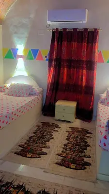 a bedroom with two twin beds with rugs on the floor at Wateen guest house in Aswan
