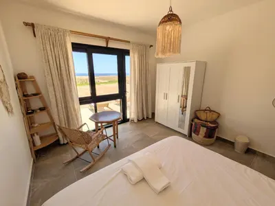 a bedroom with a bed and a chair and a window at Seafront 3BR Soma Bay Villa With Exquisite Views in Hurghada