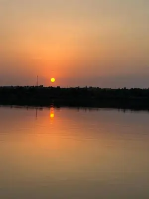 a sunset over a body of water with the sun setting at Assuan Felucca in Aswan