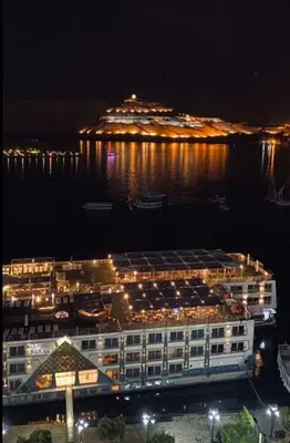 a large building with a cruise ship in the water at night at Sun of Aswan Stay in Aswan
