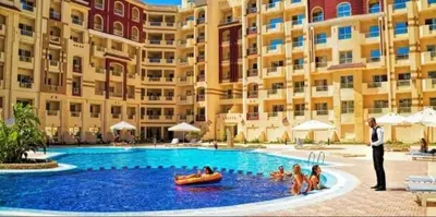 a man in a suit standing in a swimming pool in front of a building at Florenza compound in Hurghada
