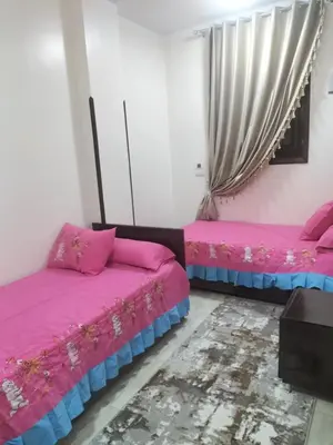 two beds in a room with pink and blue sheets at El faraón egipcio apartment in Al Karnak