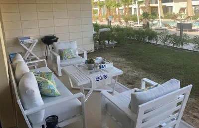 a patio with white chairs and a table and a table and chairs at Modern 3BR Poolside Apt at Cribs El Gouna in Hurghada