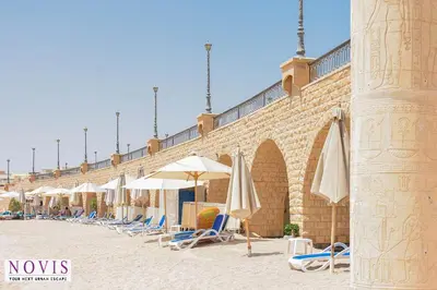 a row of chairs and umbrellas on a beach at Novis Holiday Homes Sahl Hasheesh in Hurghada