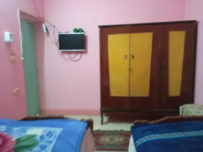 a room with two beds and a cabinet with yellow doors at هاي موود in Jazīrat Aswān