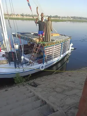 a group of three men standing on the front of a boat at Felucca Alaska in Aswan