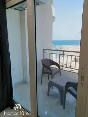 a room with a balcony with a chair and the ocean at La quinta hights in Hurghada
