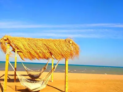 a straw umbrella and a hammock on a beach at El-Gouna in Hurghada