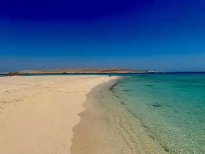 a beach with a person walking on the water at Luxury Newly Built 2 DOUBLE bedroom and living room with Beach Access and Pool in Hurghada, Egypt in Hurghada