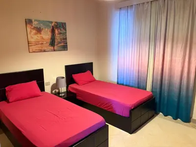 a room with two beds with red sheets and a window at Azzurra Sea&pool View 2Bedrooms in Hurghada