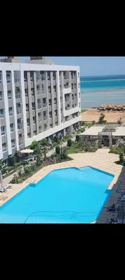 a large building with a large blue swimming pool next to the beach at Fanadir bay resort in Hurghada