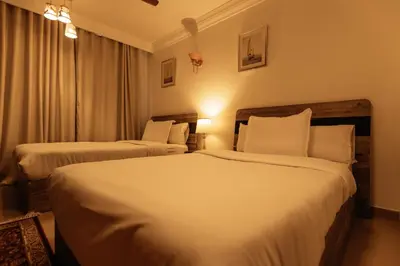 two beds in a hotel room with white sheets at Aswan Heritage Residence-Nile View and Free Airport Pickup in Aswan