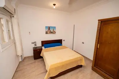 a bedroom with a bed and a dresser at White Flower Flats in Luxor