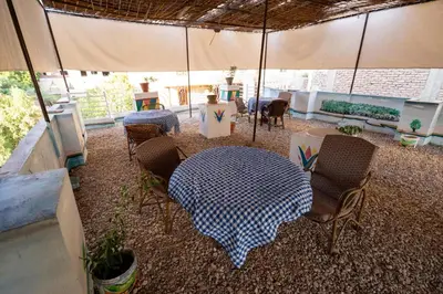 a patio with a table and chairs and an umbrella at White Flower Flats in Luxor