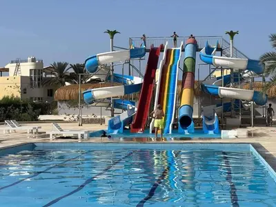 a boy is standing in front of a water slide at Fanadir bay Al Ahyaa in Hurghada