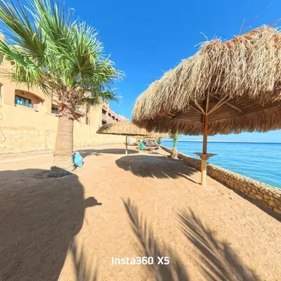 a beach with some straw umbrellas and the water at New chalet with sea view and private beach access 82m in Hurghada