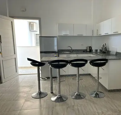 a kitchen with four bar stools in front of a counter at Aqua Palms 2 bedroom apartment - Hurghada Egypt in Hurghada