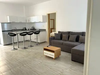 a living room with a couch and chairs and a kitchen at Aqua Palms 2 bedroom apartment - Hurghada Egypt in Hurghada