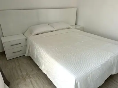 a bedroom with a white bed and a night stand at Aqua Palms 2 bedroom apartment - Hurghada Egypt in Hurghada