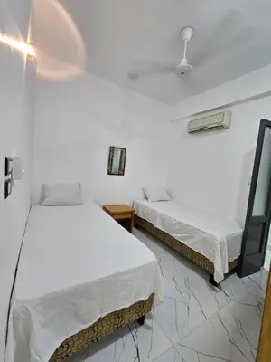 two beds in a room with white walls at Hatschepsut hous in ‘Ezbet Abu Ḥabashi