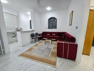 a living room with a red couch and a table at Hatschepsut hous in ‘Ezbet Abu Ḥabashi