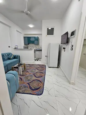 a living room with a blue couch and a kitchen at Hatschepsut hous in ‘Ezbet Abu Ḥabashi