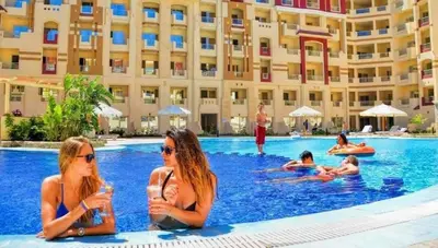two women sitting in the swimming pool at a hotel at كمبوند فلورنزا خمسين عرابيا in Hurghada