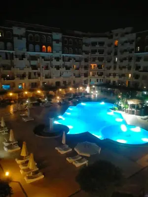 a large swimming pool in front of a building at night at كمبوند فلورنزا خمسين عرابيا in Hurghada
