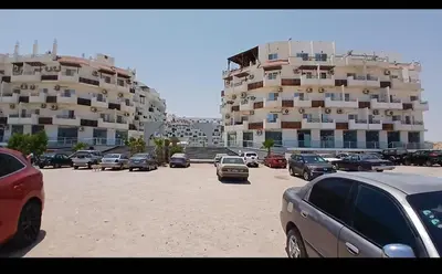 a parking lot with cars parked in front of a large building at شاليه فندقي فاخر كومباوند طيبة فيو حي الوزراء in Hurghada