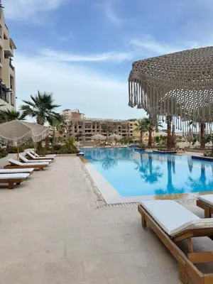 a pool at a resort with chaise lounge chairs at Aldau Heights Modern Serenity Studio in Hurghada