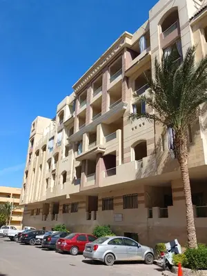 a large apartment building with cars parked in front of it at Cozy studio in Florenza Khamsim - I409 in Hurghada