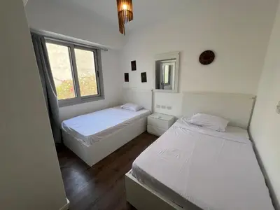two beds in a room with two windows at Bright 2Bdr with Stunning Pool Views – Sholan 1 in Hurghada
