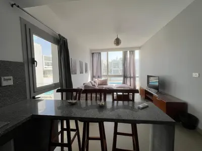 a kitchen and living room with a table and chairs at Bright 2Bdr with Stunning Pool Views – Sholan 1 in Hurghada