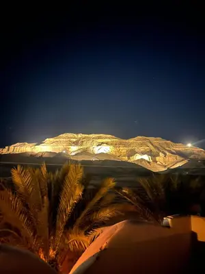 a view of a mountain at night with palm trees at Habu Palace in Luxor