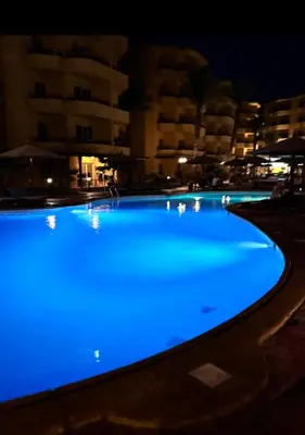 a swimming pool lit up blue at night at Elegant 2BR Retreat in Secure Resort Community in Hurghada