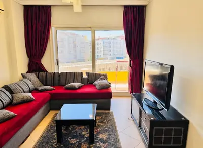 a living room with a red couch and a flat screen tv at Elegant 2BR Retreat in Secure Resort Community in Hurghada