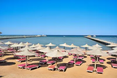 a bunch of chairs and umbrellas on a beach at Al karma aqua beach in Hurghada