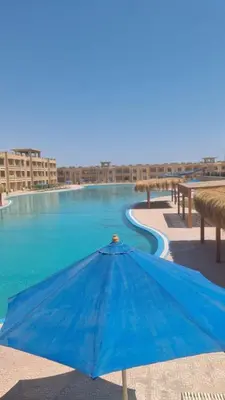 a blue umbrella sitting next to a swimming pool at Bay View, Sahl Hashish in Hurghada