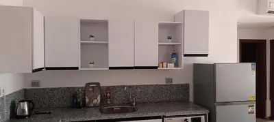 a kitchen with white cabinets and a sink and a refrigerator at 2 bedroom apartment Bay View sahl hasheesh in Hurghada