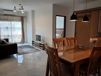 a dining room and living room with a table and chairs at Flat 10 minutes from the airport in Hurghada