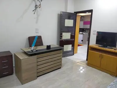 a living room with a tv and a desk with a television at Apartment in villa in Magawish in Hurghada