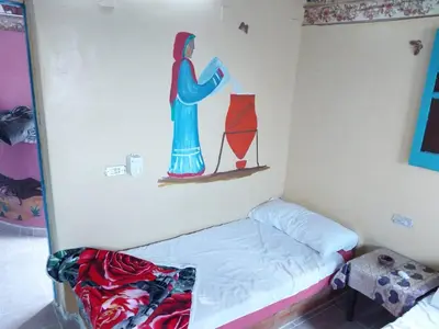 a small bed in a room with a painting on the wall at Shamandora Nubian Guest House in Jazīrat Fīlah