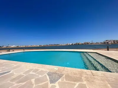 a swimming pool next to a body of water at Cyan Luxe Retreat 3Bdr in Hurghada