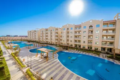 an image of an apartment complex with a large swimming pool at Chic studio at a modern resort in Hurghada
